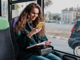 Reiziger kijkt op haar smartphone tijdens een busrit