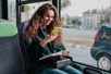 Reiziger kijkt op haar smartphone tijdens een busrit